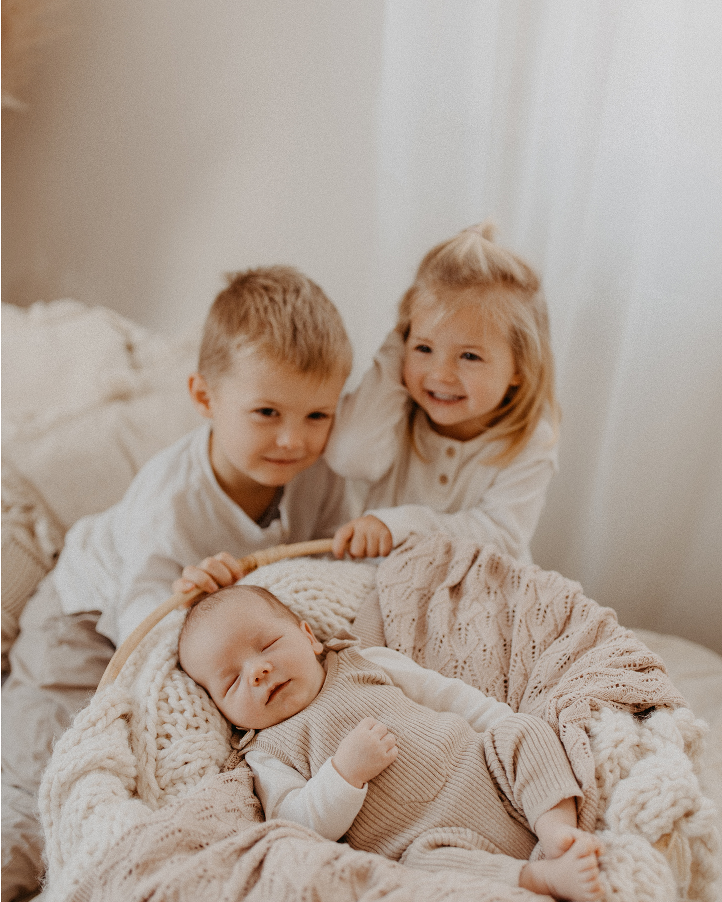Schlafendes Baby im Babykorb mit Bruder und Schwester