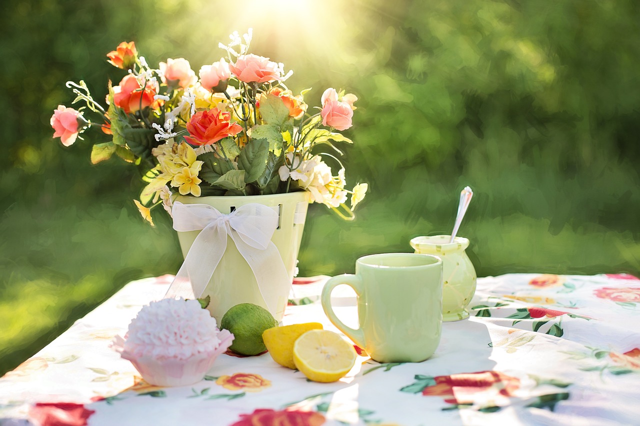 Blumen auß dem Tisch mit Kaffee und Cupcake draußen in der Sonne
