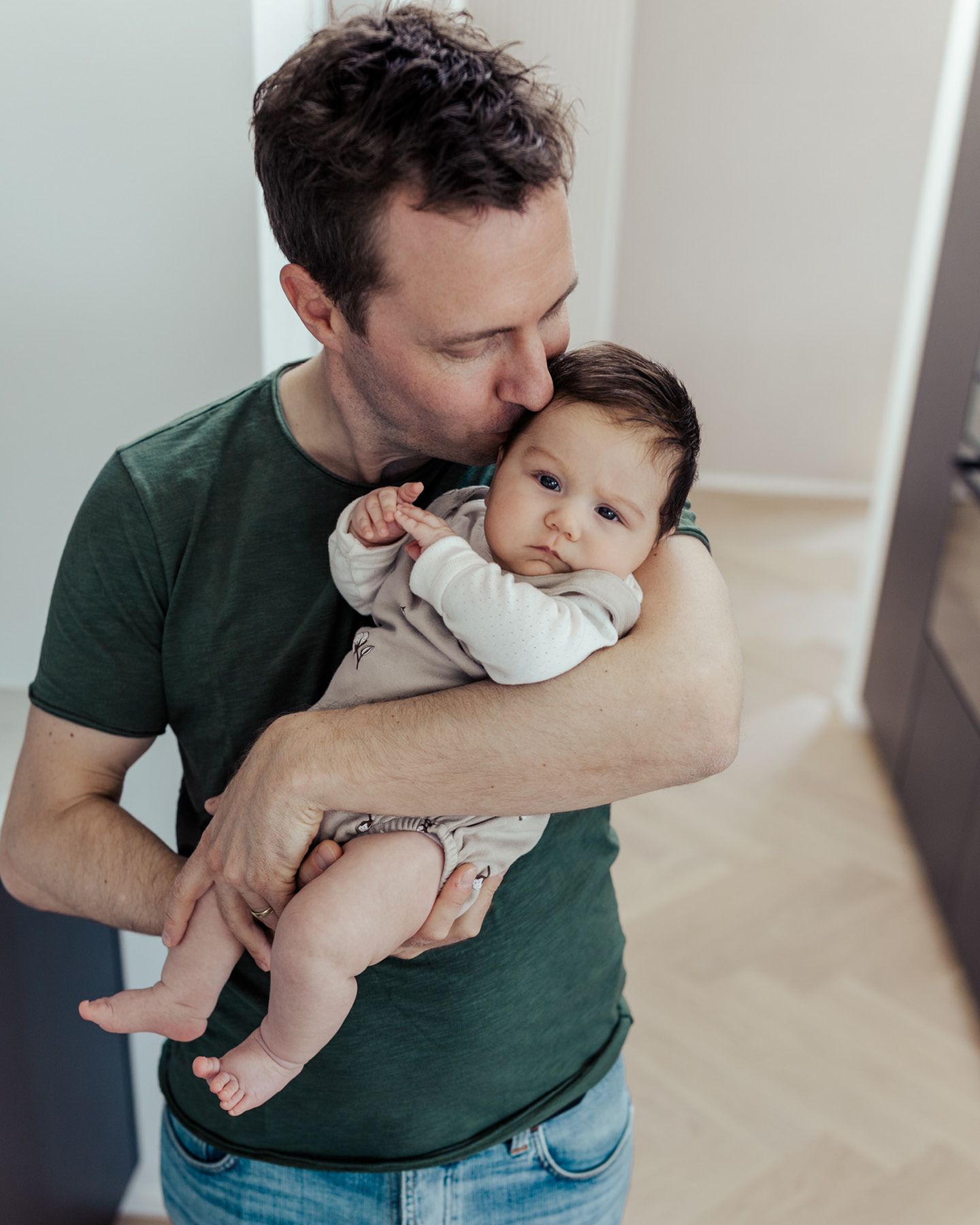 Vaterküsst sein Baby, das er auf dem Arm hält