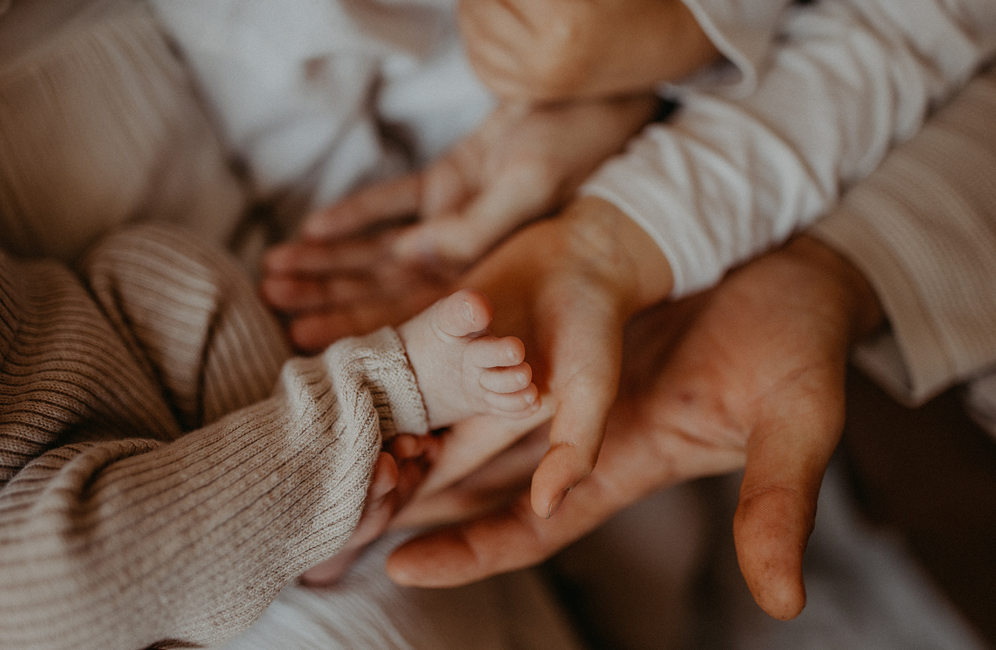 Babyfuß mit Händen der Eltern
