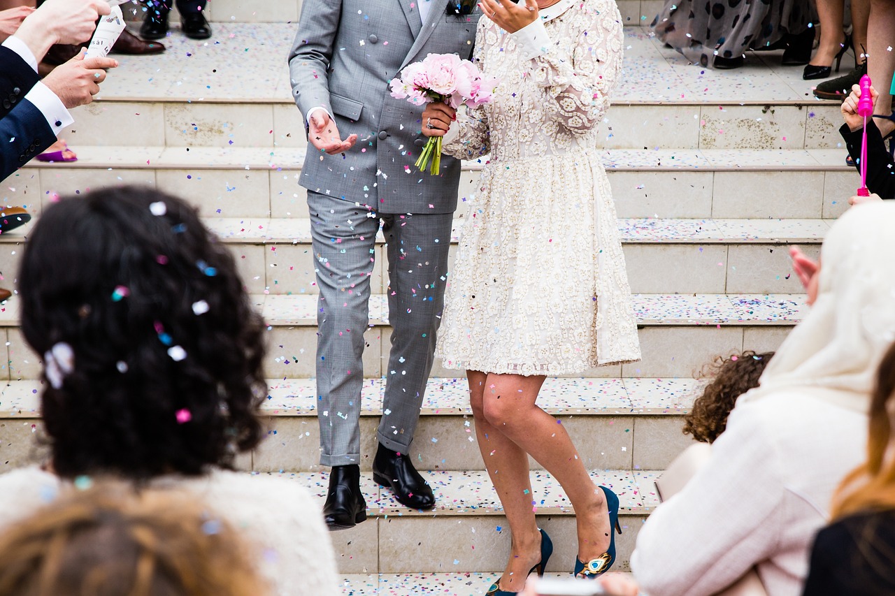 Hochzeitspaar geht raus über Treppen und es fliegt Konfetti durch die luft