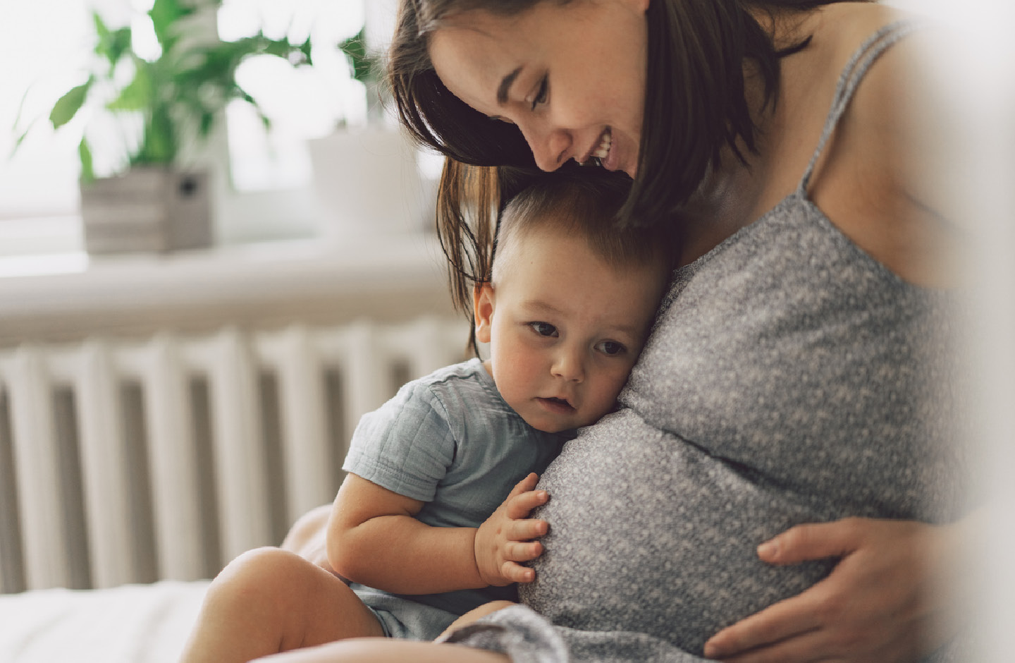 Schwangere Frau kuschelt mit kleinem Sohn