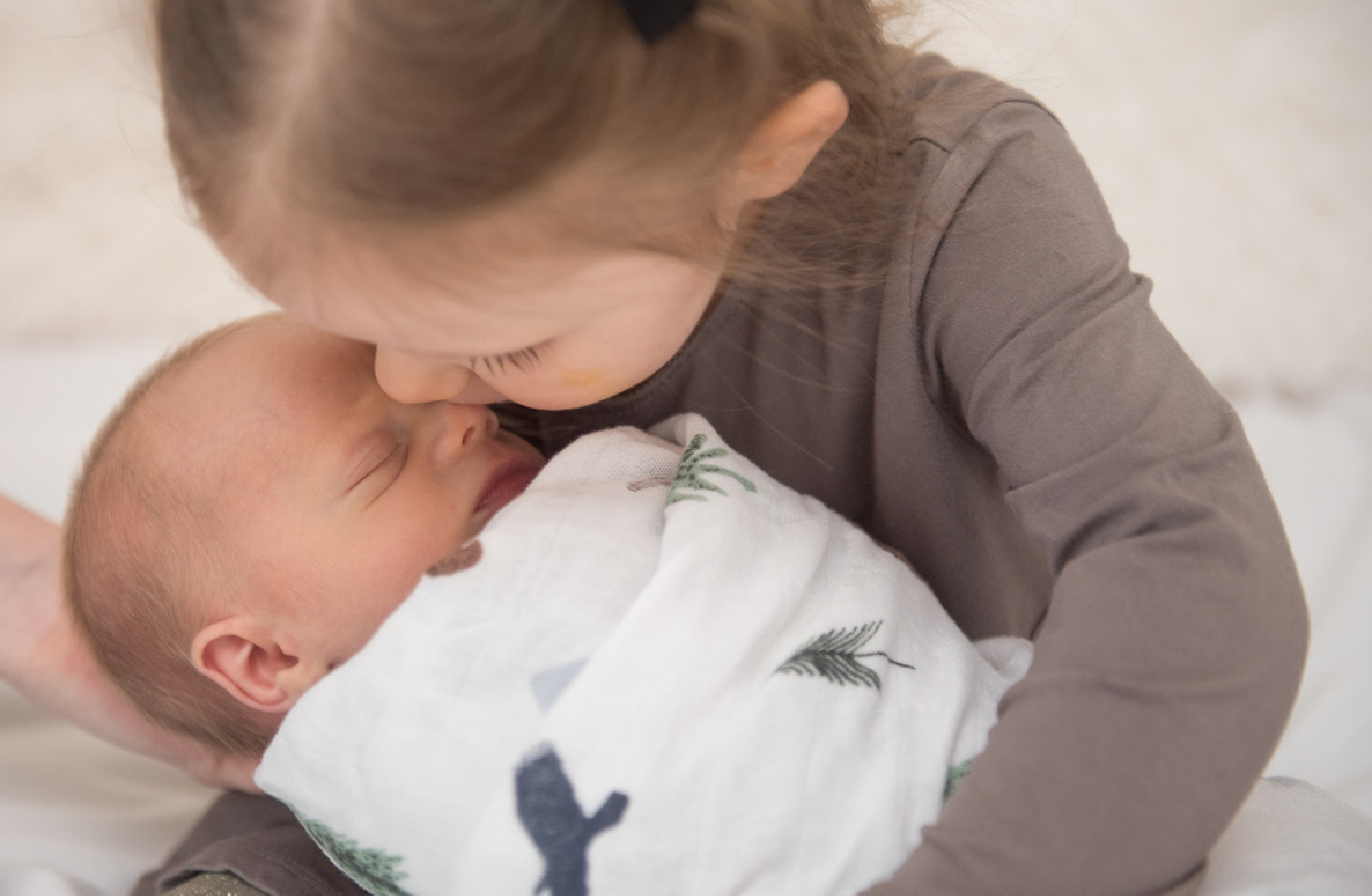 Kleines Mädchen küsst schlafendes Baby