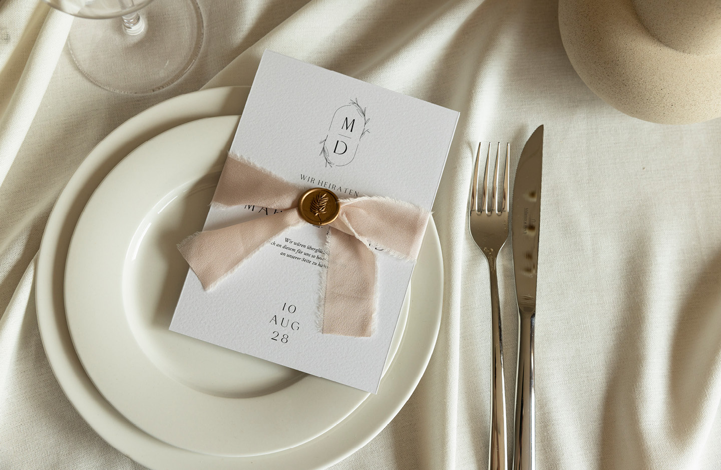 Hochzeitseinladung mit Schleife auf einem Teler liegend