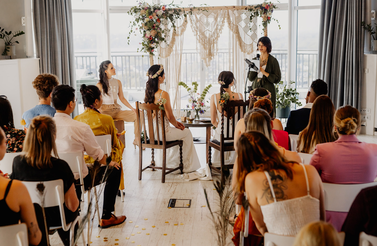 Weibliches Hochzeitspaar bei seiner Trauung mit Familie und Freunden