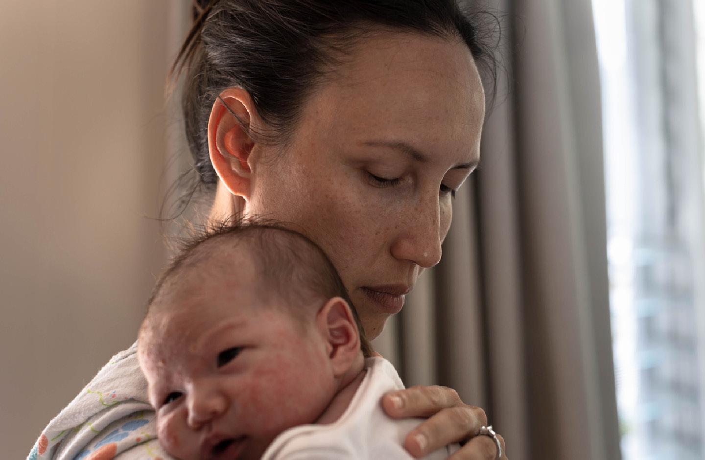 Erschöpfte Mutter mit Baby auf dem Arm