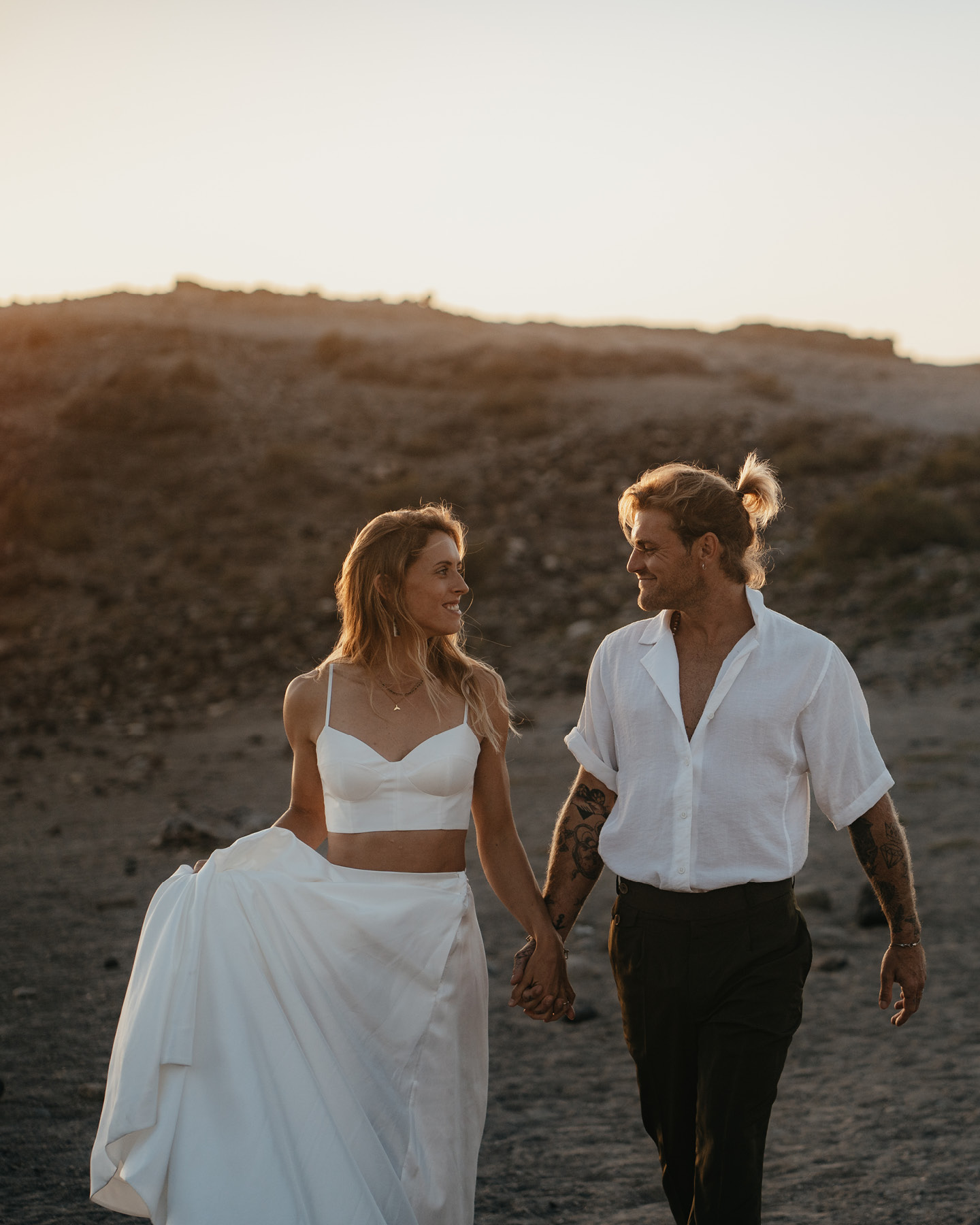 Hochzeitspaar in lässig-elegantem Outfit Hand in Hand am Strand